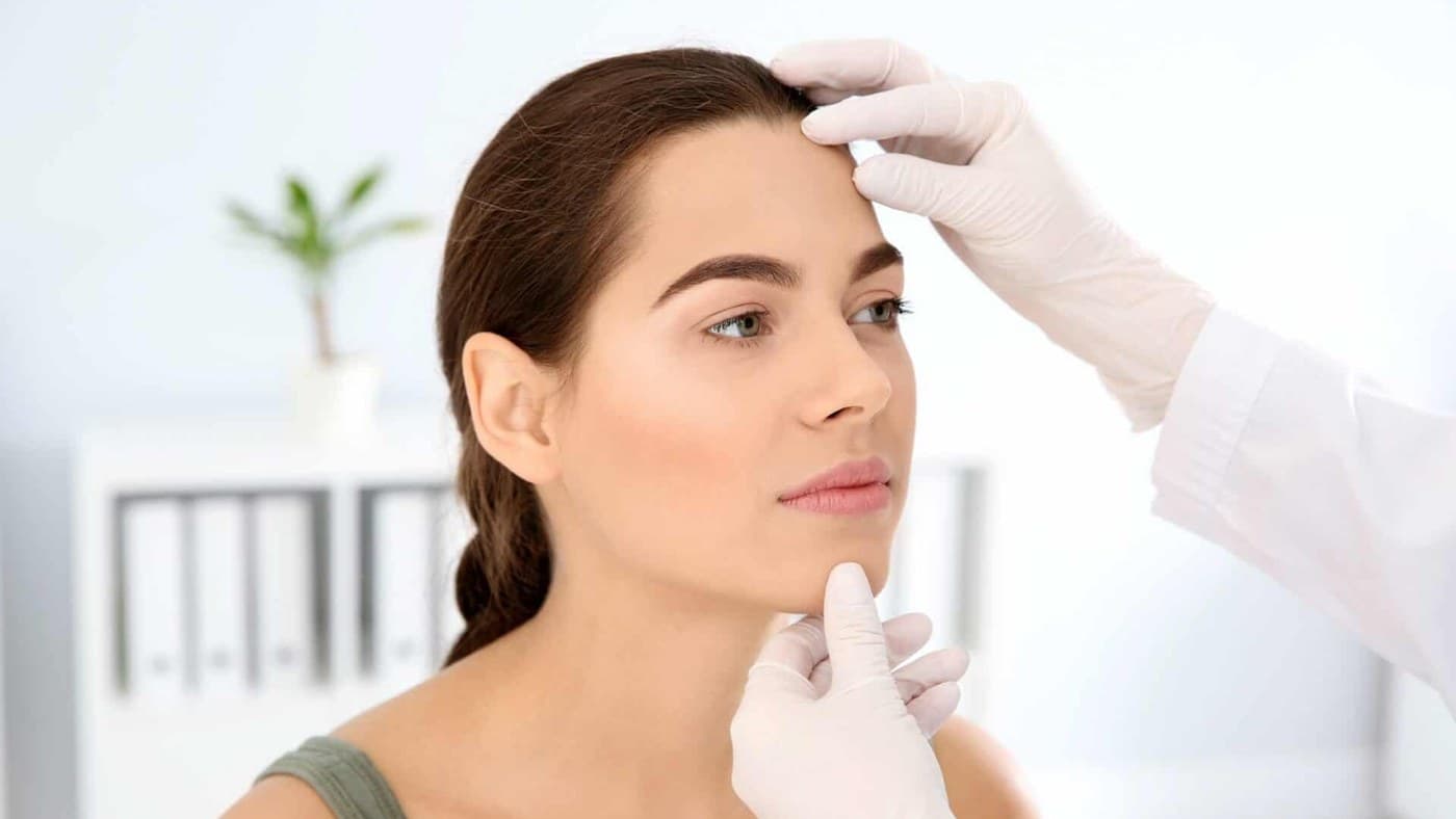 A dermatologist assessing a patient’s forehead and brow before Botox treatment
